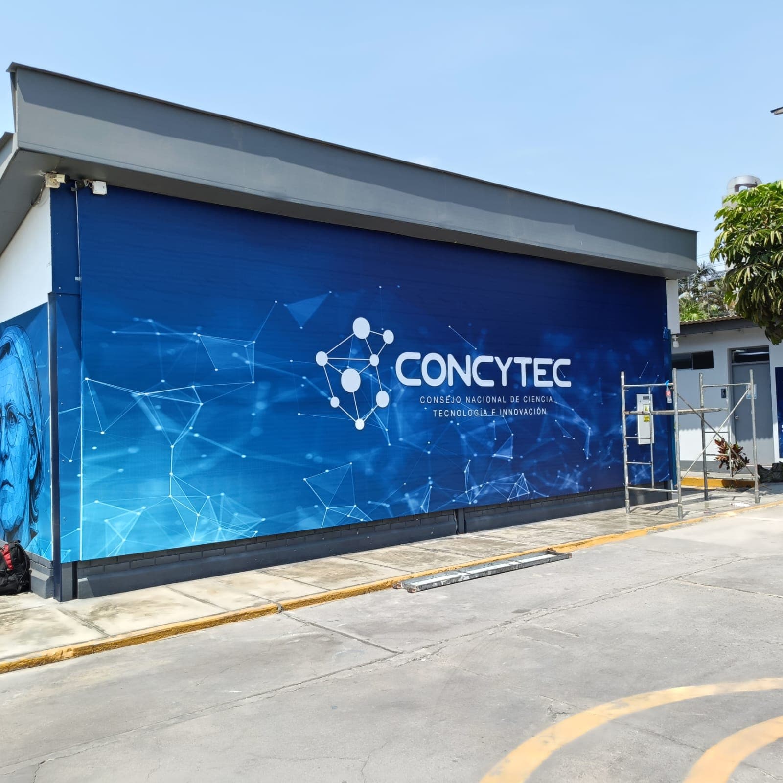 Fachada azul de CONCYTEC con gráficos tecnológicos y logotipo blanco